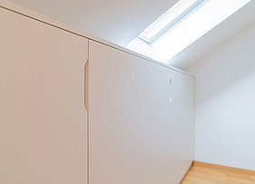 Portrait Begehbarer Kleiderschrank mit schicken MDF-Fronten in Weiß und einem Innenleben aus Echtholz unter der Dachschräge im geschlossenen Zustand
