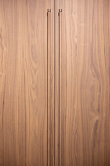 Holzfront mit vertikaler Maserung und integrierten, durchgehenden Griffleisten in abgestimmter Holzoptik
