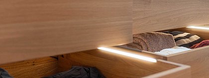 Schubkasten im geöffneten Zustand mit Beleuchtung und Kleidung