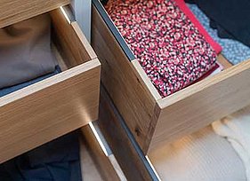 Portrait Begehbarer Kleiderschrank unter der Dachschräge mit geöffneten Schubkasten und Blick in den Schubkasten.