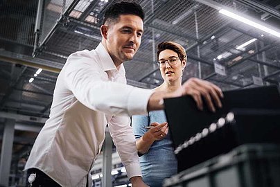 Zwei Personen in einer Arbeitssituation vor einer Produktionsanlage